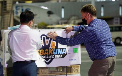 <p><strong>GOVT-PROCURED JABS.</strong> Assistant Secretary Wilben Mayor (left), head of strategic communications on current operations of the National Task Force against Covid-19, and US Embassy Political Counselor Edward Vincent O’Bryan place the Resbakuna sticker on the shipment containing 859,950 doses of the government-procured Pfizer Covid-19 vaccine that arrived at NAIA Terminal 3 in Pasay City on Monday (Dec. 13, 2021). Mayor said the new shipment of Pfizer will be used to boost the pediatric vaccination program. <strong><em>(PNA photo by Avito Dalan)</em></strong></p>