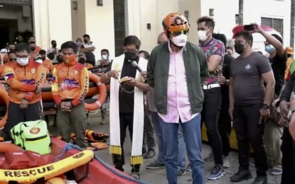 <p><strong>PREPARED.</strong> Mayor Michael Rama is seen wearing a rescuer's helmet as a priest blesses the responders who are placed on 24-hour standby in preparation for the entry of Tropical Storm Rai (Odette), in front of the Cebu City Hall on Tuesday (Dec. 14, 2021). Rama placed the city under a state of preparedness due to the incoming typhoon.<em> (Screengrab from Cebu City PIO video)</em></p>