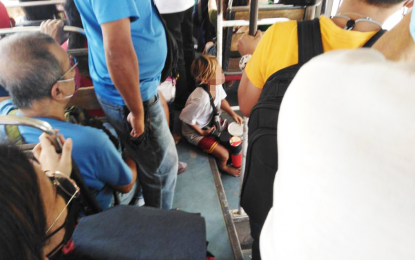 <p><strong>BUS CAROLER</strong>. A young boy sits on the floor of a passenger bus while playing with his improvised drums in exchange for a few coins on Dec. 14, 2021. During the Christmas season, kids, including members of the Badjao ethnic group, are a common sight caroling on the streets. <em>(PNA photo by Meyo de Jesus)</em></p>