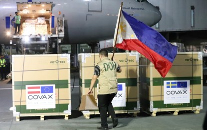 <p><strong>FOR THE PHILIPPINES.</strong> A staff of the Department of Health plants the Philippine flag near the boxes containing the Janssen Covid-19 vaccine at the Ninoy Aquino International Airport Terminal 3 in Pasay City on Tuesday (Dec. 14, 2021). This latest shipment of 1,778,400 doses of the single-shot vaccine was donated by the governments of Austria and Sweden.<em> (PNA photo by Robert Oswald P. Alfiler)</em></p>