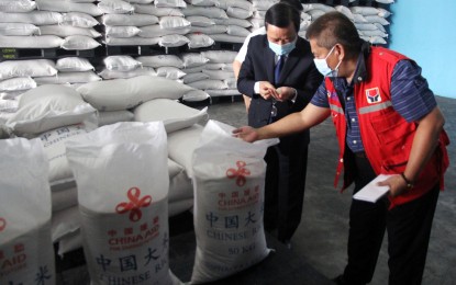 <p><strong>RICE DONATION.</strong> Chinese Ambassador Huang Xilian (left) shows the quality of the China-donated rice to Social Welfare and Development Director Emmanuel Privado at the DSWD National Resource Operations Center in Pasay on Wednesday (Dec. 22, 2021). At least 756,000 families are set to benefit from the rice donation. <em>(Photo by Ben Briones)</em></p>