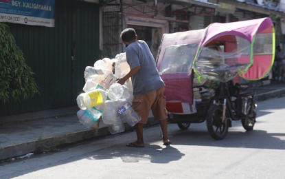 <p><strong>CASH FOR TRASH.</strong> A man collects used plastic bottles which he will sell to junk shops in Novaliches, Quezon City in this undated photo. Senator Loren Legarda said Monday (Jan. 23, 2023) that she will pursue the approval of her bill that calls for a total ban on single-use plastics. <em>(PNA photo by Oliver Marquez)</em></p>