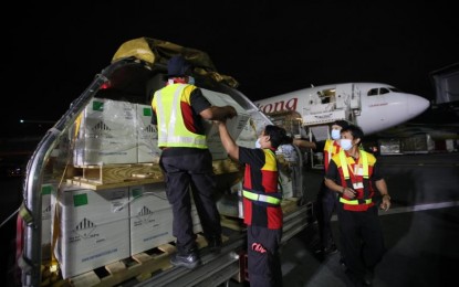 <p><strong>MORE PFIZER DOSES.</strong> Airport personnel offload cargoes containing 1,187,550 doses of Pfizer-BioNTech Covid-19 vaccine at the NAIA Terminal 3 in Pasay City on Monday night (Dec. 27, 2021). The newly delivered shipment is part of the government-procured Covid-19 vaccines through the Asian Development Bank. <em>(PNA photo by Avito Dalan)</em></p>
