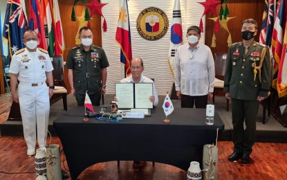 <p><strong>SIGNED.</strong> Defense Secretary Delfin Lorenzana (center) shows the copy of the signed contract with South Korean shipbuilder Hyundai Heavy Industries in a virtual ceremony at the DND main office in Quezon City on Tuesday (Dec. 28, 2021). The contract is for the acquisition of two brand-new missile corvettes worth PHP28 billion for the Philippine Navy. <em>(Photo courtesy of DND)</em></p>