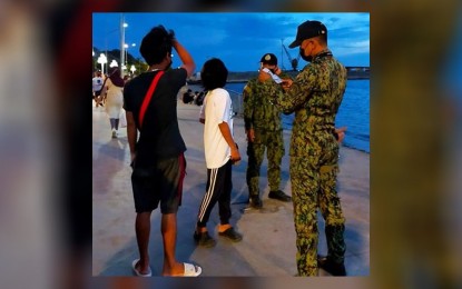 <p><strong>HEALTH PROTOCOL VIOLATION.</strong> A policeman issues a citation ticket to two strollers caught violating the health protocols on Sunday (Dec. 26, 2021) along the R.T. Lim Boulevard in Zamboanga City. Enforcement of health protocols continued in Zamboanga City, which has recorded over 21,000 cumulative coronavirus disease 2019 (Covid-19) recoveries since March last year.<em> (Photo courtesy of the Zamboanga City Police Office)</em></p>