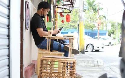 <p><strong>SECURE FUNDS.</strong> A man uses his mobile phone while having coffee outside a coffee shop on Scout Limbaga Street, Barangay Sacred Heart, Quezon City on Dec. 29, 2021. Digital payments app Gcash assured its customers that their funds are "safe and secure" following the temporary downtime on May 9, 2023. <em>(PNA photo by Robert Oswald P. Alfiler)</em></p>