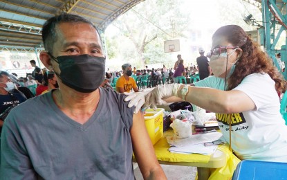 <p><strong>THIRD SHOT.</strong> Severiano Dolatre, 61, gets his AstraZeneca booster shot from Maribeth Sotto, a midwife, at the covered court of Bagong Silang Elementary School in Caloocan City on Jan. 6, 2022. The additional layer of protection against Covid-19 is proven to almost eliminate the chances of developing severe symptoms of Covid-19. <em>(PNA photo by Ben Briones)</em></p>