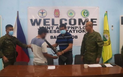 <p><strong>RIGHT MOVE.</strong> Seok Panday, a 35-year-old member of the Bangsamoro Islamic Freedom Fighters-Kagui Karialan faction operating in the borders of North Cotabato and Maguindanao provinces, turns over his M16 rifle to Mayor Romeo Arana in Midsayap, North Cotabato during his surrender on Thursday (Jan. 6, 2022). Looking on are Lt. Colonel Edgardo Vilchez Jr. (right), commander of the Army’s 34th Infantry Battalion, and other military officials. <em>(Photo courtesy of 34IB)</em></p>