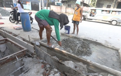 <p><strong>ROAD REPAIR.</strong> Construction workers mix gravel, sand, and cement for drainage cement casting along Zapote Road in Caloocan City on Jan. 11, 2022. The Department of Environment and Natural Resources recommends that cement makers explore ways to utilize plastic waste as raw materials to help reduce the country’s solid waste by at least 40 percent. <em>(PNA photo by Oliver Marquez)</em></p>