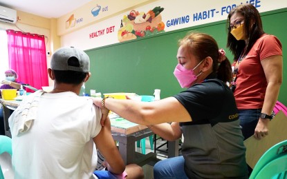 <p><strong>JABS FOR TEENS.</strong> Midwife Brigida De Leon administers the Covid-19 vaccine to Sebastian Pimentel, 16, inside a classroom of Bagong Silang Elementary School in Caloocan City on Jan. 11, 2022. Pimentel was one of the 500 who received the first dose of the Pfizer jab.<em> (PNA photo by Ben Briones)</em></p>