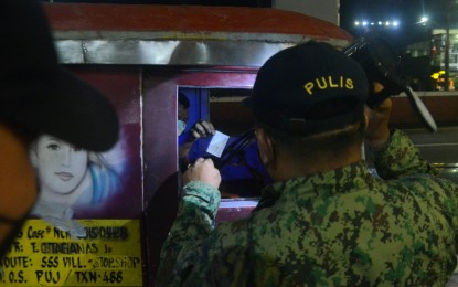 <p><strong>STRICT PROTOCOL.</strong> A member of the Quezon City Police District asks for a jeepney driver’s vaccination card at a checkpoint in Cubao on Thursday night (Jan. 13, 2022). Passersby who aren’t vaccinated are given warnings and advised to set schedules with the local government so they can get jabs. <em>(PNA photo by Robert Oswald P. Alfiler)</em></p>