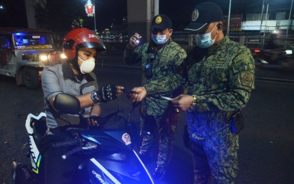 <p><strong>CHECKPOINT.</strong> A motorcycle rider stops at a checkpoint at the corner of Aurora Blvd. and Pinatubo St., Barangay San Martin De Porres, Cubao, Quezon City on Thursday night (Jan. 13, 2022). Police checkpoints have so far arrested 144 gun ban violators.<em> (PNA photo by Robert Oswald P. Alfiler)</em></p>