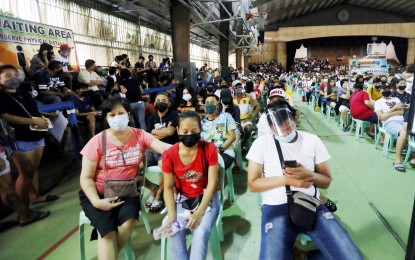 <p><strong>WAITING IN LINE.</strong> Hundreds of people wait for their turn to get vaccinated against the coronavirus disease 2019 on Monday (Jan. 17, 2022) at the covered court of Notre Dame School in Caloocan City. As of January 13, over 54 million Filipinos or more than 70 percent of the country's target population have been fully vaccinated against the disease. <em>(PNA photo by Oliver Marquez)</em></p>