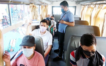 <p><strong>VAX CARDS UP.</strong> Passengers show their vaccination cards to the bus conductor (in blue polo) inside an e-jeepney before leaving the terminal at the corner of Soliven and Litex Road along Commonwealth Avenue, Quezon City on Monday (Jan. 17, 2022). Under the "no vaccination, no ride” policy in Metro Manila, travelers who have medical conditions preventing them from being vaccinated against Covid-19 are exempted provided they show a valid and duly signed medical certificate with the name and contact details of their doctors.<em> (PNA photo by Ben Briones)</em></p>