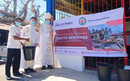 <p><strong>RELIEF OPS.</strong> Dumaguete Bishop Julito Cortes (right) and Jimalalud parish priest Fr. Dalmacio Heramis, give relief goods to a Typhoon Odette victim during the town fiesta on Jan. 15, 2022. The Diocese of Dumaguete prelate announced the simultaneous Holy Masses on January 24 for those who perished in the storm.<em> (Photo from the Diocese of Dumaguete-Typhoon Odette Response's Facebook page)</em></p>