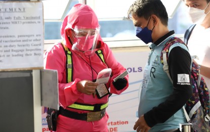 <p><strong>VAX CARD CHECK.</strong> A passenger of the Metro Rail Transit-3 Quezon Avenue station in Quezon City brings out his vaccination card as a requirement for boarding on Tuesday (Jan. 18, 2022). Only vaccinated individuals with a physical or digital copy of their vaccination cards and a valid identification with photo are allowed to ride in public transportation while the unvaccinated must show proof of exemption, like medical or employment certificates. <em>(PNA photo by Robert Oswald P. Alfiler)</em></p>