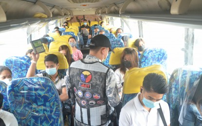 <p><strong>VAX CHECK.</strong> An Inter-Agency Council for Traffic officer checks the vaccination cards of passengers inside a bus as part of the "no vax, no ride policy" along Mindanao Avenue, Quezon City on Jan. 20, 2022. The Department of Transportation on Monday reiterated that the policy is "legally valid" and is necessary to help "maintain and preserve safe travel". <em>(PNA photo by Robert Oswald P. Alfiler)</em></p>