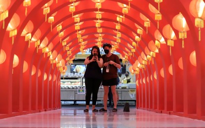 <p><strong>PHOTO OPPORTUNITY.</strong> The Tunnel of Chinese Lanterns at a Quezon City mall is the perfect spot for a Chinese New Year photo for these two mall-goers on Tuesday (Feb. 1, 2022). Only fully vaccinated customers are allowed in the city’s malls, unless for purchase of essential goods or availing of services such as medical treatment. <em>(PNA photo by Robert Oswald P. Alfiler)</em></p>