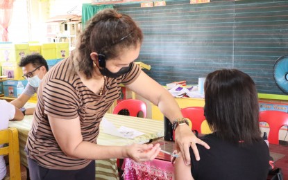 <p><strong>PROTECTION.</strong> A woman receives her Covid-19 vaccine at an elementary school in Pamplona, Negros Oriental on Jan. 28, 2022. Health authorities are urging people to get vaccinated amid reports that 90 percent of Covid-19 deaths in the province were unvaccinated. <em>(Photo courtesy of Negros Oriental Facebook)</em></p>