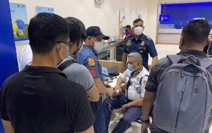 <p><strong>DUTY.</strong> A bank security guard (sitting center) surrenders after shooting an alleged "scammer" inside a shopping mall in Cagayan de Oro City, Friday (Feb. 4, 2022). The police report said the guard responded to the calls of two persons chasing the alleged scammer. <em>(Photo courtesy of Cagayan de Oro City Police Office)</em></p>