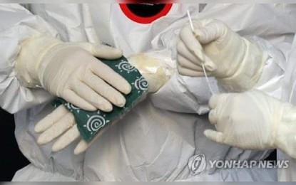 <p><strong>RECORD HIGH</strong>. Medical workers warm their hands with an instant hot pack at an outdoor Covid-19 testing station in Seoul on Feb. 5, 2022, as the mercury dropped to a low of minus 9 degrees Celsius. South Korea’s daily virus cases hit another high 38,691 Sunday, as the highly transmissible Omicron variant rages across the country following a holiday season. <em>(Yonhap photo)</em></p>