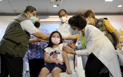 <p><strong>KIDS' TURN.</strong> Dr. Moriel Creencia, Medical Center Chief II of the National Children's Hospital in Quezon City, administers the reformulated Pfizer Covid-19 jab to a girl on Monday (Feb. 7, 2022). The pilot rollout of the vaccination for the 5 to 11 age group was also witnessed by (from left) National Task Force Against Covid-19 special adviser Dr. Teodoro Herbosa, US Embassy Chargé d'Affaires Heather Variava, NTF chief Secretary Carlito Galvez Jr., and NTF medical consultant Dr. Ma. Paz Corrales. <em>(PNA photo by Joey O. Razon)</em></p>