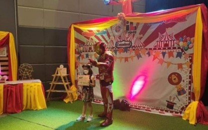 <p><strong>VAX FOR KIDS.</strong> A young girl poses with a character mascot wearing an Iron Man costume at the SM Aura SMX vaccination center in Taguig City on Monday (Feb. 7, 2022). The city adopted a "superhero carnival" theme in two vaccination centers for the rollout of Covid-19 jabs for kids aged 5 to 11. <em>(PNA photo by Lloyd Caliwan)</em></p>