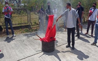 <p><strong>NO TO REDS.</strong> A former member of the Kalipunan ng Damayang Mahihirap (Kadamay) burns a communist flag during the mass surrenders of some 600 members of the leftist group on Wednesday (Feb. 9, 2022). The surrenderers also pledged their allegiance to the government and denounced the communist movement.<em> (Photo courtesy of PNP)</em></p>