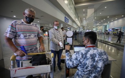 <p><strong>PH REOPENS TO INT'L TOURISTS.</strong> Two foreign tourists present their QR codes upon arrival at the Ninoy Aquino International Airport on Thursday (Feb. 10, 2022). At least 398 foreign tourists arrived on the first day of the country's reopening to fully vaccinated international travelers.<em> (PNA photo by Avito Dalan)</em></p>