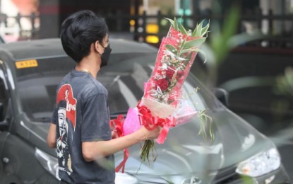 <p><strong>KEEPING UP WITH TRADITION.</strong> A man walks away with flowers purchased at a makeshift shop along Libertad Street in Pasay City on Sunday (Feb. 13, 2022). Despite the prevailing Covid-19 crisis, social media was flooded with photo and stories of Valentine’s Day celebrations on Monday. <em>(PNA photo by Avito Dalan)</em></p>