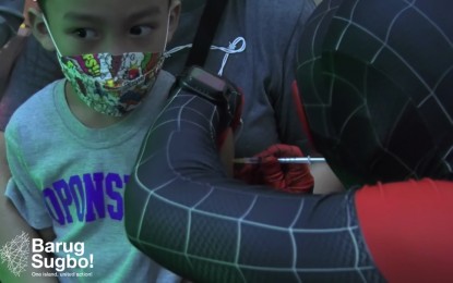 <p><strong>KIDS' VAX</strong>. This undated photo shows a nurse sporting a Spiderman costume while administering a specially-prepared Covid-19 vaccine jab to a child at the Ayala Center Cebu. Dr. Mary Jean Loreche, DOH-7 chief pathologist, on Friday (Feb. 18, 2022) said vaccination for children aged 5 to 11 is doing well in Metro Cebu, with about 6,000 getting their first dose during the first five days. <em>(Screengrab from Cebu City PIO video)</em></p>