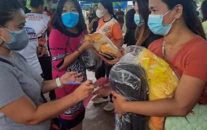 <p><strong>RELIEF AID.</strong> A fire victim receives sleeping gear as the city government mobilizes its resources to help fire victims who are temporarily housed at the covered court in Sitio Taluingung, Barangay San Roque, Zamboanga City on Feb. 18, 2022. A total of 149 families were displaced by a fire that hit a closely built community Thursday (February 17) in Barangay San Roque. <em>(Photo courtesy of City Hall PIO)</em></p>