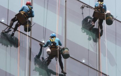 <p><strong>HIGH POST.</strong> Not minding the risks, workers clean the glass wall of a high-rise building in Bonifacio Global City, Taguig City in this February 2022 photo. The world celebrates International Workers' Day on Sunday (May 1). <em>(PNA photo by Avito Dalan)</em></p>