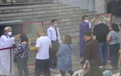 <p><strong>ASH WEDNESDAY</strong>. Fr. Nestor Bandalan (right), with the help of another priest, administers ash to the Catholic faithful on Ash Wednesday (March 2, 2022) at the Basilica Minore del Sto. Niño in Cebu City. Cebu Archbishop Jose Palma released a video message urging the people to intensify prayers amid the uncertainties brought by the conflict between Russia and Ukraine. <em>(Screengrab from Basilica Minore del Sto. Niño video)</em></p>