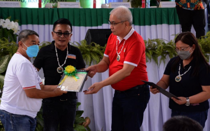 <p><strong>E-TITLES.</strong> Agrarian Secretary Bernie Cruz (2nd from left), Aklan 2nd District Rep. Teodorico Haresco Jr., and Western Visayas Regional Director Sheila Enciso lead the distribution of e-titles under the Support to Parcelization of Lands for Individual Titling (SPLIT) Project of DAR in Naisud Covered Court, Barangay Naisud, Ibajay, Aklan in this undated file photo. A total of 179 electronic land titles have been distributed to agrarian reform beneficiaries in Western Visayas. <em>(Contributed photo)</em></p>