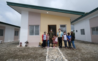 <p><strong>PEACE COMMUNITY.</strong> Presidential Adviser on Peace, Reconciliation, and Unity, Secretary Carlito Galvez Jr. (6th from left), poses with a Kapatiran member family during the ceremonial turnover of housing units in Ibajay, Aklan on Thursday (March 10, 2022). The housing units are part of the government’s commitment to help former communist terrorist group members rebuild their lives.<em> (Photo courtesy of OPAPRU)</em></p>