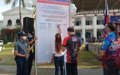 <p><strong>COVENANT SIGNING.</strong> Laoag mayoral candidate Chevylle Farinas signs a covenant for peace as incumbent Vice Mayor Vicentito Lazo and Mayor Michael M. Keon look on. Farinas, Lazo, and Keon are vying for Laoag's mayoral post in the May polls. <em>(Contributed photo)</em></p>