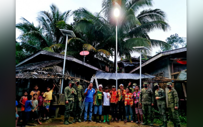 <p><strong>NEW LIGHTS, NEW HOPE.</strong> Military officials, along with the indigenous community leaders in Sitio Nasilaban, Barangay Palma Gil, Talaingod, Davao Del Norte, pose for posterity during the ceremonial lighting of the solar lights Monday evening (March 21, 2022). Dubbed as 'Suga sa Katawhan,' the 400 solar streetlights will be distributed to 32 sub-communities of the barangay and are expected to illuminate the main Panpan Road.<em> (PNA photo by Che Palicte)</em></p>
