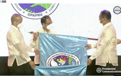 <p><strong>OPAPRU</strong>. Presidential Adviser on Peace, Reconciliation and Unity Secretary Carlito Galvez Jr. (center) leads the raising of the new flag of the Office of the Presidential Adviser on Peace, Reconciliation and Unity (OPAPRU) on Wednesday (March 23, 2022) at the PICC in Pasay City. OPAPRU officially transitioned from the Office of the Presidential Adviser on the Peace Process (OPAPP). <em>(Screengrab from RTVM live stream)</em></p>