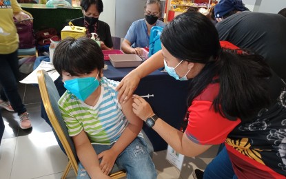 <p><strong>JABBED</strong>. A nine-year-old boy receives the second dose of Pfizer Covid-19 vaccine at the SM City Bacolod inoculation site on March 18, 2022. Vaccination hubs in major malls will continue to accommodate vaccinees while the city government will dispatch more vaccinators to the barangays and deploy Vax-i buses to reach more minors and those needing booster shots.<em> (PNA Bacolod file photo)</em></p>
