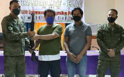 <p><strong>TIRED AND HUNGRY.</strong> One of the eight members of the Abu Sayyaf Group (ASG) rebels who surrendered Thursday (March 31, 2022) hands over his firearm to government authorities during a ceremony held at the municipal hall of Talipao municipality in Sulu province. Abu Tubah, an ASG surrenderer, revealed that hunger and exhaustion pushed them to lay down their arms and go back to their families.<em> (Photo courtesy of Joint Task Force Sulu)</em></p>