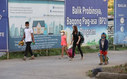 <p><strong>BALIK PROBINSYA</strong>. Pedestrians walk past a Balik-Probinsya, Bagong Pag-Asa (BP2) program tarpaulin in this undated photo. In Bicol, a total of 400 families who benefited from the government program have received a total of PHP15.3 million in cash assistance, a Department of Social Welfare and Development (DSWD) official said Tuesday (Aug. 16, 2022).<em> (PNA file photo)</em></p>
