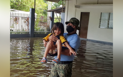 <p><strong>RESCUED.</strong> A police officer carries a child after water suddenly swelled in Barangay Limbo, Sultan Kudarat, Maguindanao on Monday (April 11, 2022). About 76,131 families have been affected by the continuous rains dumped by Tropical Depression Agaton in the Bangsamoro Autonomous Region in Muslim Mindanao. <em>(Photo courtesy of the Sultan Kudarat municipal government)</em></p>