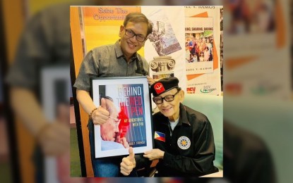 <p><strong>LEGACY. </strong>Former president Fidel V. Ramos (seated) receives a framed copy of the cover of the book on his presidency, “Behind the Red Pen”, from author Jojo Terencio in this undated photo. Ramos died Sunday (July 31, 2022) at the age of 94. <em>(Photo courtesy of The FVR Presidential Library)</em></p>