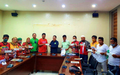 <p><strong>IRA FUNDS.</strong> Village officials show their checks of PHP100,000 each as part of the Bangsamoro Autonomous Region in Muslim Mindanao subsidy to non-IRA recipient villages in Maguindanao. They received the checks Monday (April 18, 2022) from Interior Minister Naguib Sinarimbo (center in dark blue jacket) at the Ministry of the Interior and Local Government  office in Cotabato City. <em>(Photo courtesy of MILG-BARMM)</em></p>