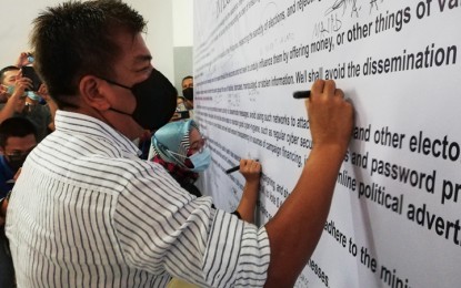 <p><strong>INTEGRITY PLEDGE</strong>. incumbent Basilan Rep. Mujiv Hataman of the Basilan Unity Party and one of his three opponents, Lawyer Yasmeen Junaid of the United Bangsamoro Justice Party (partly hidden), sign the Integrity Pledge on Saturday (April 23, 2022) vowing to adhere to existing laws for the peaceful and orderly conduct of the elections on May 9. The activity was held at the Basilan State College Amphitheater and initiated by the Commission on Elections.<em> (Photo by Teofilo P. Garcia Jr.)</em></p>