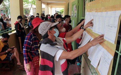 <p><strong>SEARCHING FOR NAMES</strong>. Voters at the Gov. P. F. Espiritu Elementary School, Barangay Panapaan III in Bacoor City, Cavite look for their names during the May 9, 2022 election day. The Commission on Elections en banc is studying to partially proclaim party-list winners based on the figures they currently have. <em>(PNA photo by Gil Calinga)</em></p>