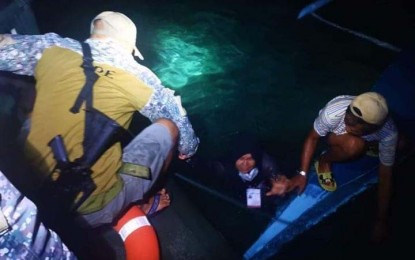 <p><strong>RESCUED AT SEA.</strong> A marine soldier assigned with the Small Unit Riverine Craft (left) helps pull out a woman Monday evening (May 9, 2022) from the waters of Bongao, Tawi-Tawi. The troops were fetching electoral board members and vote-counting machines at Lato-Lato Elementary School when they noticed distress light signals at sea, prompting them to render assistance. <em>(Photo courtesy of 2Mbde)</em></p>