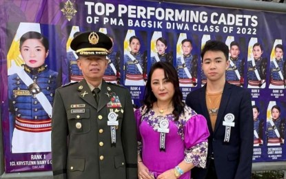 <p><strong>THE FAMILY</strong>. The Quemado family led by Col. Nicolas Sr. (left), Dr. Loveleih Quemado (center,) and Kyle, the youngest among the four Quemado siblings, pose beside the photo of Ensign Krystlenn Ivany Quemado (on background photo) who topped the graduating class of the Philippine Military Academy “Bagsik-Diwa” class of 2022 during a ceremony on Sunday (May 15, 2022). The young Quemado, in her valedictory address, said that a visit to the camp where her father had been assigned as a soldier made her want to be a soldier and graduate with honors. <em>(PNA photo courtesy of Col. Quemado)</em></p>