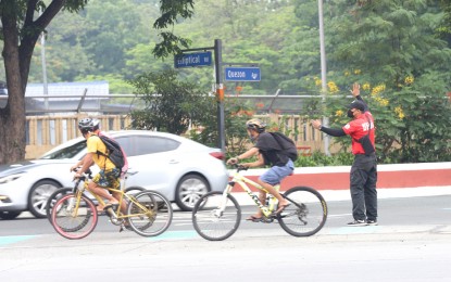 <p><strong>SAFER BIKING.</strong> A traffic enforcer helps cyclists along Elliptical Road in Quezon City on May 17, 2022. Department of Transportation (DOTr) Secretary Jaime Bautista asked relevant government agencies to push for the construction of "end-of-trip" facilities in schools to encourage students and staff to bike to and from campus. <em>(PNA photo by Robert Oswald P. Alfiler)</em></p>